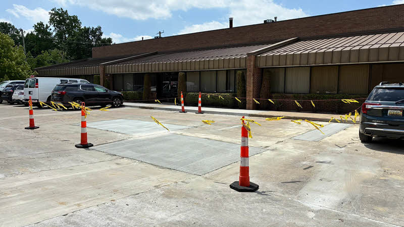 Morelli Parking Lot Paving Paved patch in a concrete parking lot with traffic cones and caution tape