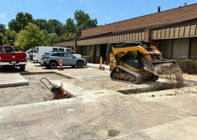 Morelli – Clinton Township, Michigan 23 Skid-steer loader working on a parking lot site with safety cones and parked vehicles