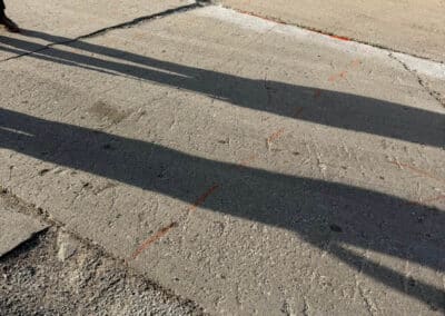Morelli – Clinton Township, Michigan 3 Concrete surface with large cracks and orange chalk lines marking the pavement