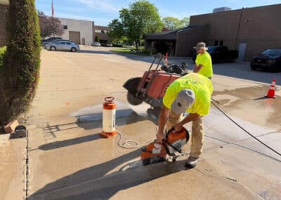 Morelli – Clinton Township, Michigan 13 Workers using a concrete cut-off saw on a damp concrete surface in a parking lot