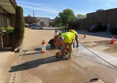 Morelli – Clinton Township, Michigan 11 Workers cutting concrete with a handheld saw in a parking lot