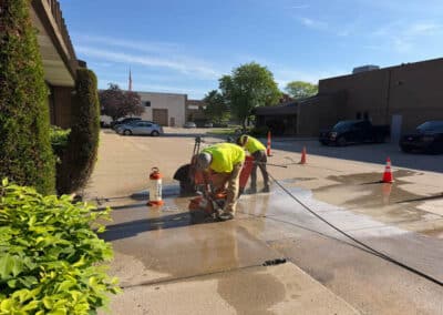 Morelli – Clinton Township, Michigan 10 Workers using a concrete grinder on a wet patch of pavement in a parking lot
