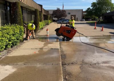 Morelli – Clinton Township, Michigan 7 Workers performing maintenance on a concrete sidewalk beside a building