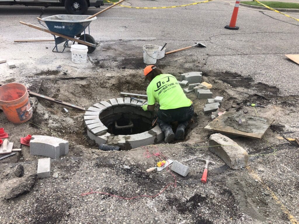 Asphalt Street Repair at Costco Construction worker repairing a cracked asphalt street at an open manhole